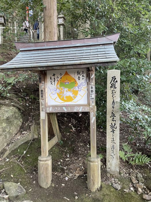 立木の観音さまにまもられての看板