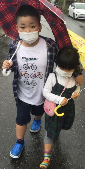 雨の日に傘を差して散歩する息子と娘