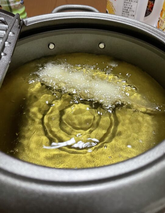 たっぷりの油でうずらの卵串を揚げる。